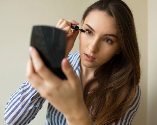 attentive_attractive_girl_applying_makeup_near_the_window_at_home_beautiful_woman_in_shirt_doing_makeup_with_mascara_brush_using_pocket_mirror_before_date_close_up_650x410.jpg
