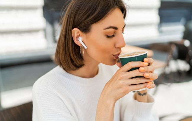 blissful_short_haired_woman_enjoing_cappucino_cafe_wearing_cozy_white_sweater_listening_favorite_music_by_earphones_650x410.jpg
